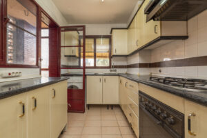 kitchen with black countertops cream cabinets gas burners some red windows door that leads drying deck 300x200 1